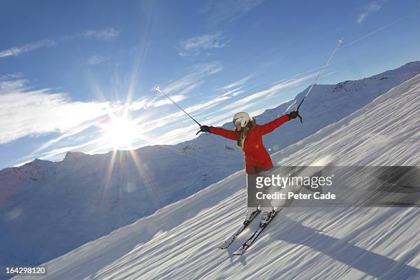 woman skiing downhill, blue sky, sun shining - val thorens fotografías e imágenes de stock