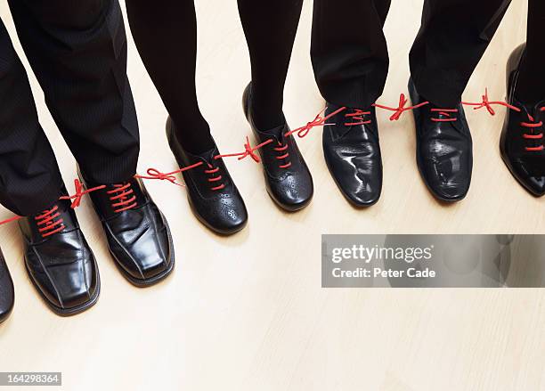 executives shoes tied together with red laces - chain stock-fotos und bilder