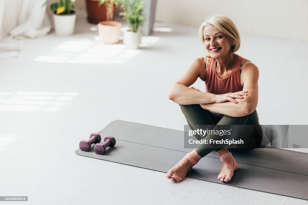 A Happy Blonde Senior Woman Looking At Camera After Doing Yoga At Home