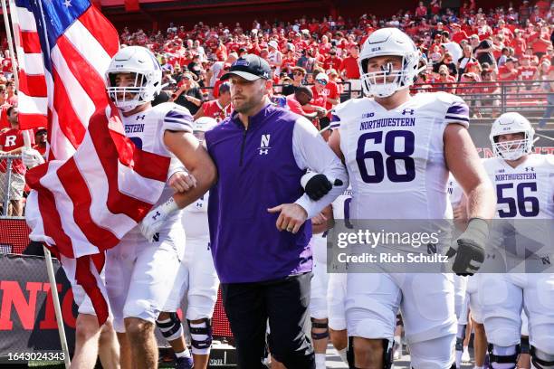 Head coach David Braun of the Northwestern Wildcats walks out onto the field with Bryce Gallagher and Josh Priebe before a college football game...