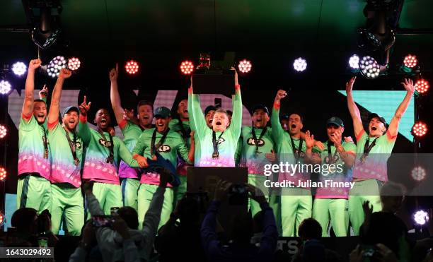 Sam Billings of Oval Invincibles lifts The Hundred Men's Champions Trophy as players of Oval Invincibles celebrate after defeating Manchester...