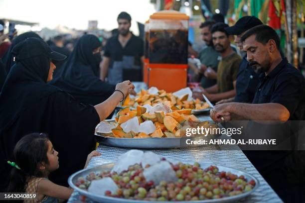 Men distribute fruits to Shiite Muslim pilgrims marching from Baghdad towards the shrine city of Karbala on September 3, 2023 ahead of the Arbaeen...