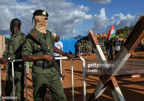 Niger's security officers stand guard as supporters of Niger's National Council of Safeguard of the Homeland gather oustide Niger and French airbase...