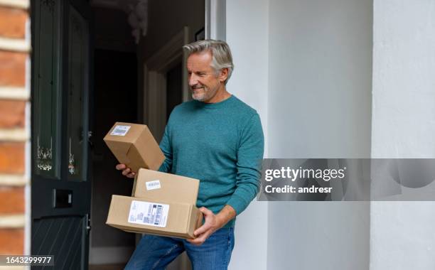uomo anziano che riceve pacchi a casa - consegna a domicilio foto e immagini stock