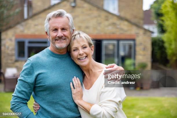 portrait of a loving senior couple smiling outside their house - 65 stock pictures, royalty-free photos & images
