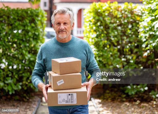 senior man receiving packages at his house - parcel delivery stock pictures, royalty-free photos & images