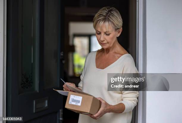 portrait of a senior woman receiving a package in the mail - elderly receiving paperwork stock pictures, royalty-free photos & images
