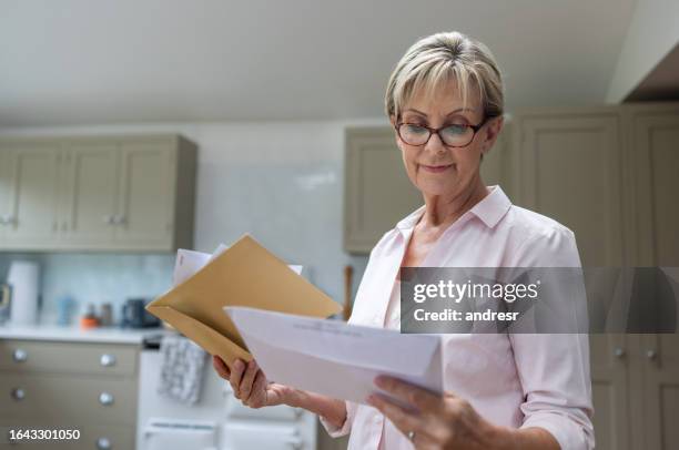 senior woman at home checking her mail - elderly receiving paperwork stock pictures, royalty-free photos & images