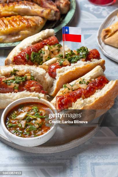 chilean food. traditional choripan with spicy pebre, chorizo sandwich with chorizo sausages and bread maraqueta. - completo stock pictures, royalty-free photos & images