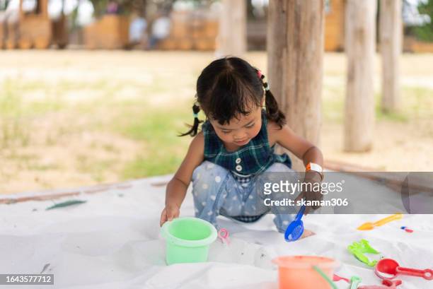 happy weekend activity asian toddler enjoy playing sandbox on the playground at public park - 2 boys 1 sandbox stock pictures, royalty-free photos & images