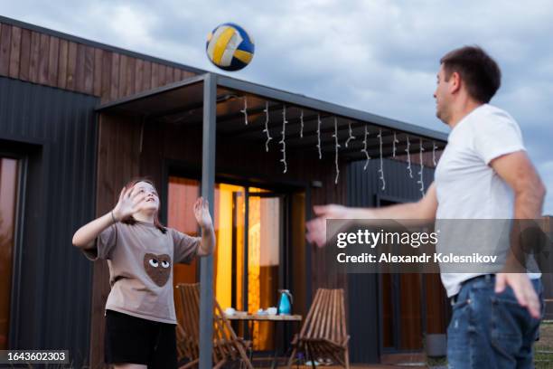 dad and daughter playing volleyball in a country house at sunset. happy family moment. summer lifestyle - volleyball park stock pictures, royalty-free photos & images