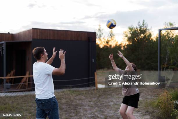 dad and daughter playing volleyball in a country house at sunset. happy family moment. summer lifestyle - volleyball park stock pictures, royalty-free photos & images