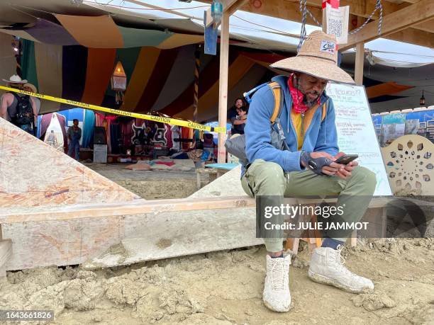 Willonius Hatcher comedian and screenwriter and AI content creator checks his phone at Black Rock City Burning man on September 3, 2023. Tens of...