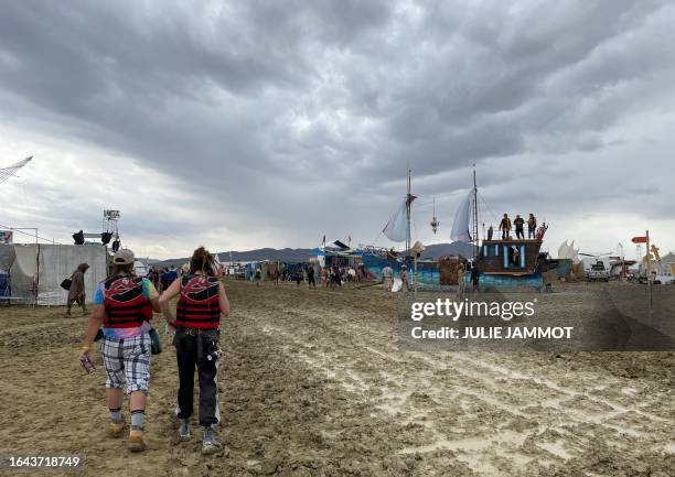 Attendees walk through a muddy desert plain on September 2 after heavy rains turned the annual Burning Man festival site in Nevada's Black Rock...