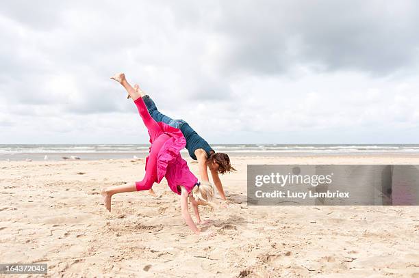 mother and daughter doing handstand on the beach - girl in dress doing handstand stockfoto's en -beelden