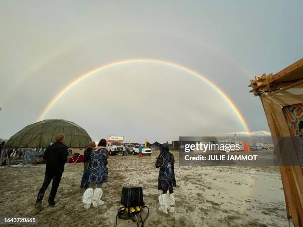 Attendees look at a double rainbow over flooding on a desert plain on September 1 after heavy rains turned the annual Burning Man festival site in...