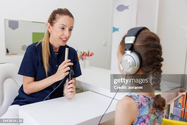 femme médecin utilisant un microphone, fille portant des écouteurs lors d’un rendez-vous audiométrique - ent photos et images de collection