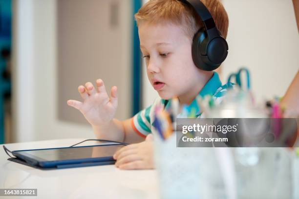 preschool boy wearing headphones and using tablet at speech therapy - description stock pictures, royalty-free photos & images