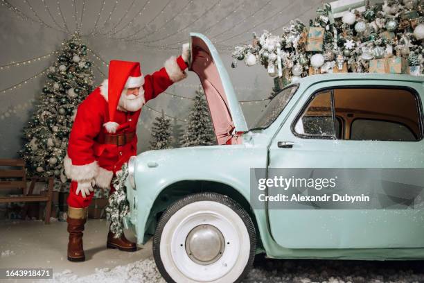 santa claus is trying to find out what broke in the car. the concept of timely car maintenance. - bonnet noel stock pictures, royalty-free photos & images