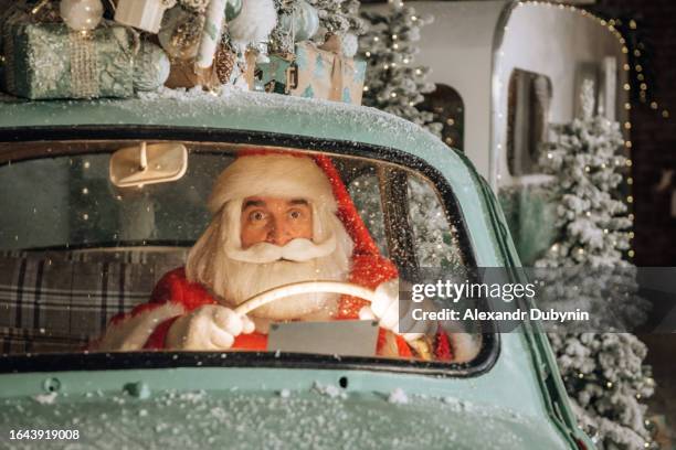 portrait of santa claus driving a car using a gift delivery application or a navigator using a gadget. - instrumento de navegación fotografías e imágenes de stock