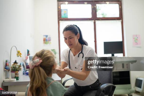 pediatrician examining little girl's throat - preventive care stock pictures, royalty-free photos & images