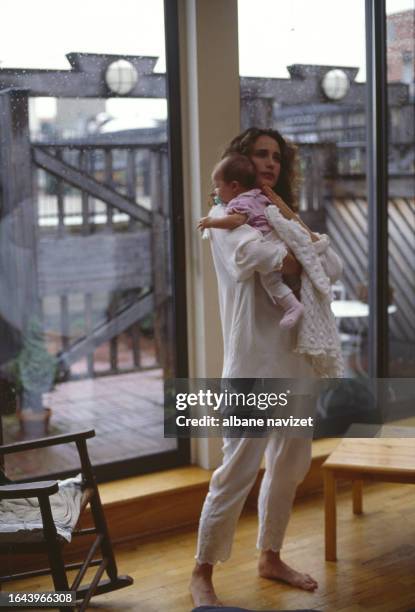 American actress Andie MacDowell holding her daughter Rainey in her arms, 1989.