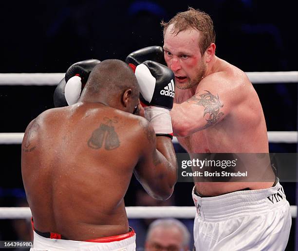 Michael Sprott of Great Britain and Robert Helenius of Finland exchange punches during the Heavyweight fight at Getec Arena on March 23, 2013 in...