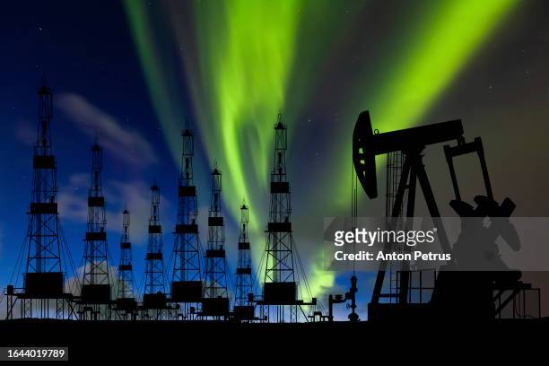 oil field with rigs and pumps on the background of the northern lights - extreme weather norway stock pictures, royalty-free photos & images