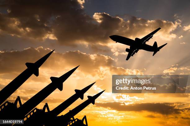 missile system and passenger airplane at sunset - zivile luftfahrt stock-fotos und bilder