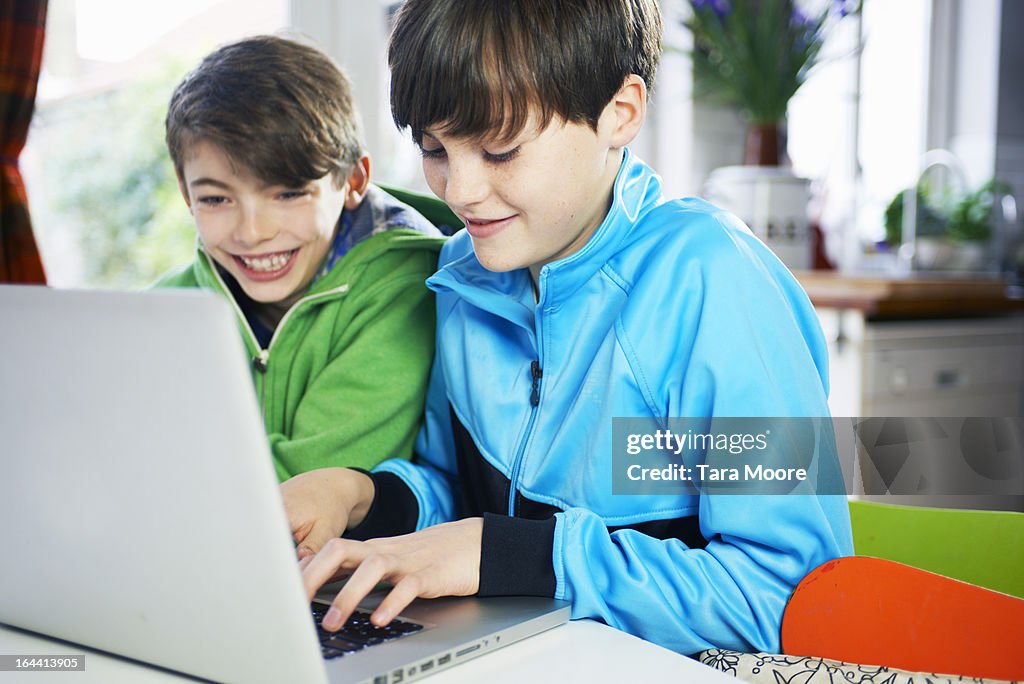 Two boys smiling looking at computer