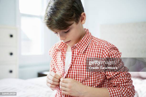 young boy getting dressed in bedroom - vestirse fotografías e imágenes de stock