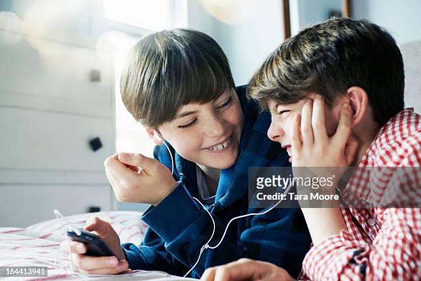 two boys listing to music on mobile with headphone - 12 12 12 2013 film stock-fotos und bilder