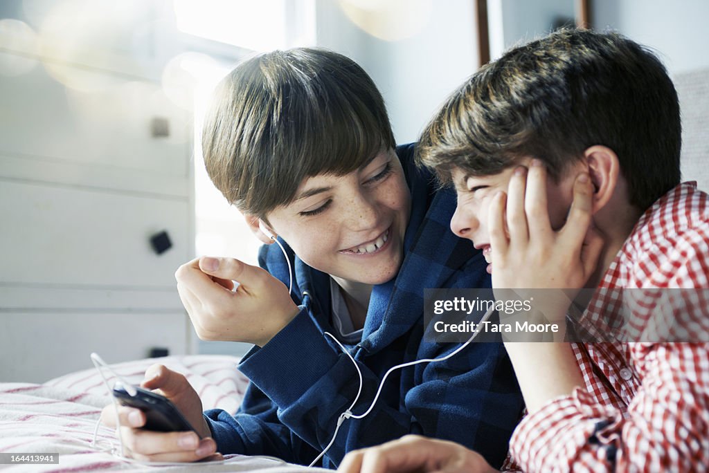 Two boys listing to music on mobile with headphone