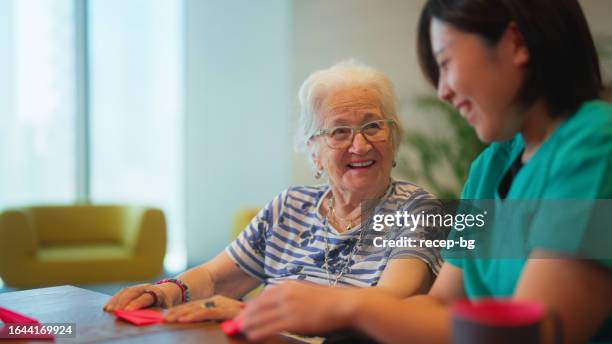 senior woman learning making origami as for physiotherapy activity - elderly cognitive stimulation therapy stockfoto's en -beelden