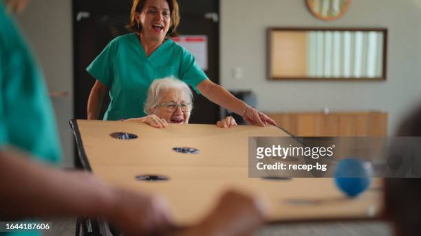two senior adult women playing games as physiotherapy in nursing home - elderly cognitive stimulation therapy stockfoto's en -beelden