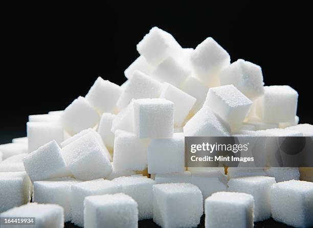 pile of sugar cubes against a black backdrop. - sugar cube stock pictures, royalty-free photos & images