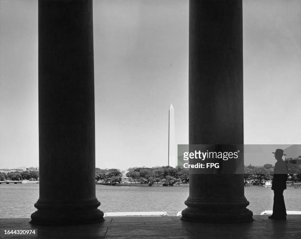 Silhouette of a man standing beside a column of the Lincoln Memorial, over the waters of the Reflecting Pool looking east toward the Washington...