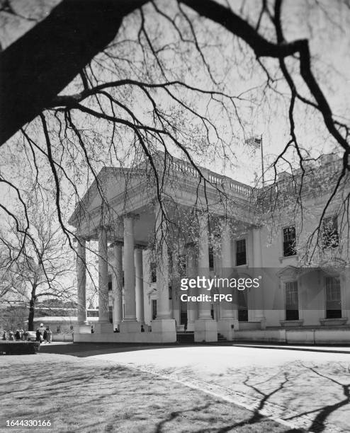 The North Portico, partially obscured by the branches of a tree, at the White House in Washington, DC, circa 1950.