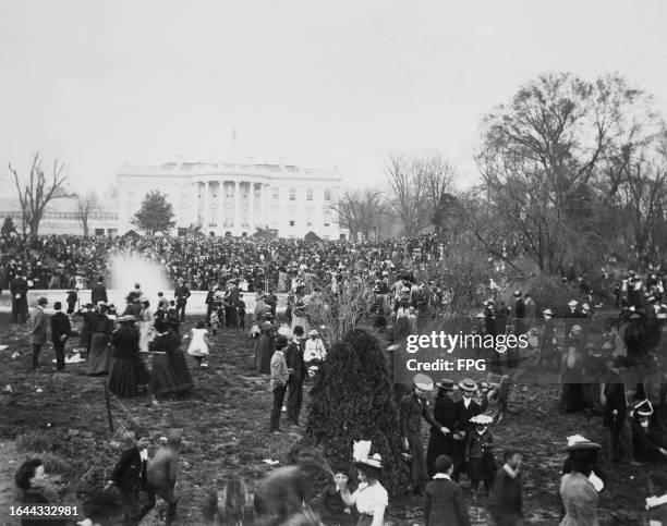 Crowds of people participate in the White House Easter Egg Roll, on the South Lawn, with the semi-circular portico of the White House in the...