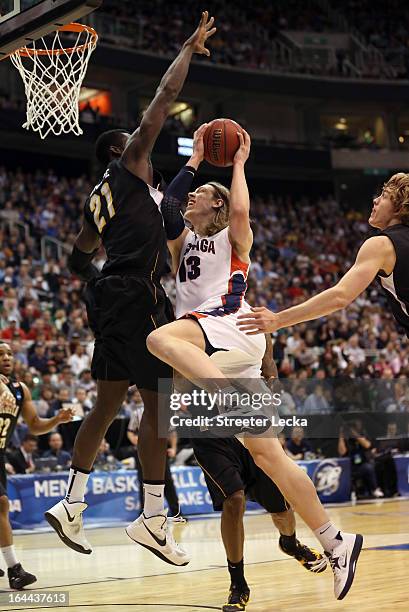 Kelly Olynyk of the Gonzaga Bulldogs goes up for a shot against Ehimen Orukpe and Carl Hall of the Wichita State Shockers in the first half during...