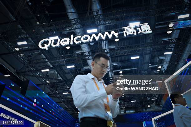 Man uses his mobile phone near a Qualcomm stall at the China International Fair for Trade in Services in Beijing on September 4, 2023.