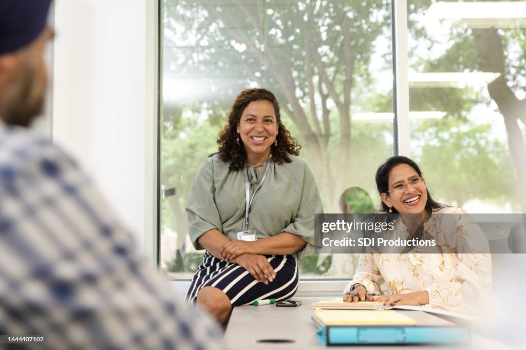 Adult students and female teacher enjoy chatting before class