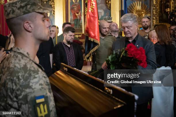 Former President of Ukraine, Petro Poroshenko, holds red roses as he stands near the coffin during the funeral ceremony of Colonel of the Armed...