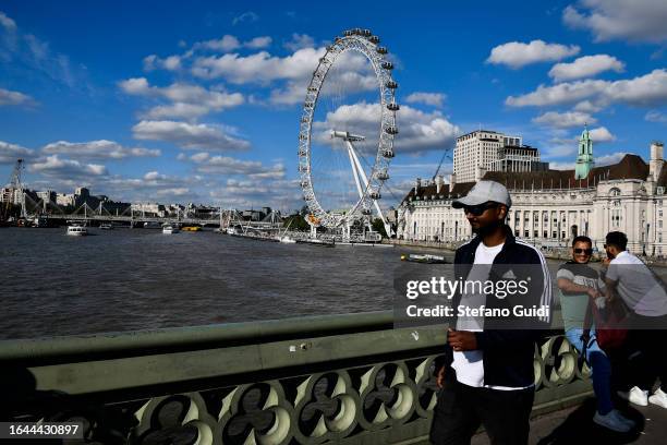 Tourists walk on Westminster Bridge with the London Eye in the background on August 21, 2023 in London, England. London is the capital of England,...