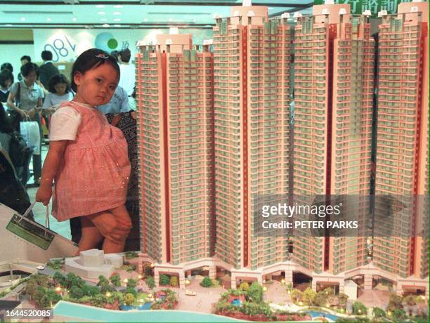 Child is distracted as her parents look at a model of a housing project at a housing sale 21 May in Hong Kong where flats have been priced at a lower...