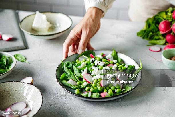 nahaufnahme einer weiblichen hand mit einem grünen salatteller auf dem küchentisch - leaf vegetable stock-fotos und bilder