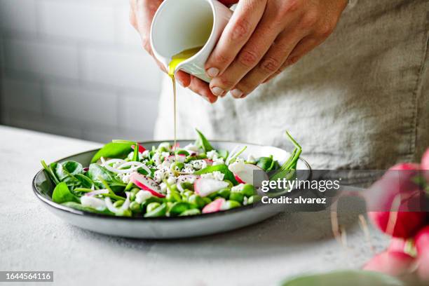 close-up of a woman preparing healthy summer green salad at home kitchen - oil stock pictures, royalty-free photos & images
