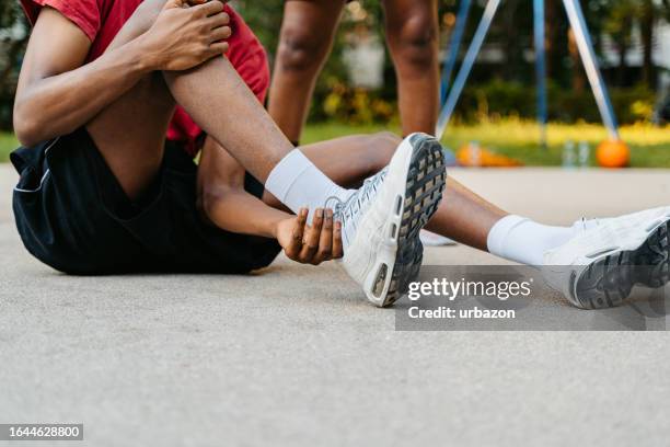 young man injuring his ankle while playing basketball - tornozelo imagens e fotografias de stock