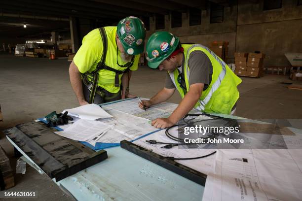 Workers check blueprints and plans inside the new parking garage of the Stamford Transportation Center on July 17, 2023 in Stamford, Connecticut....