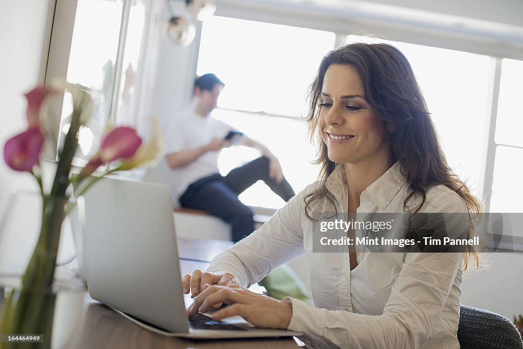 Couple at Home, Woman using Laptop and Man using Tablet